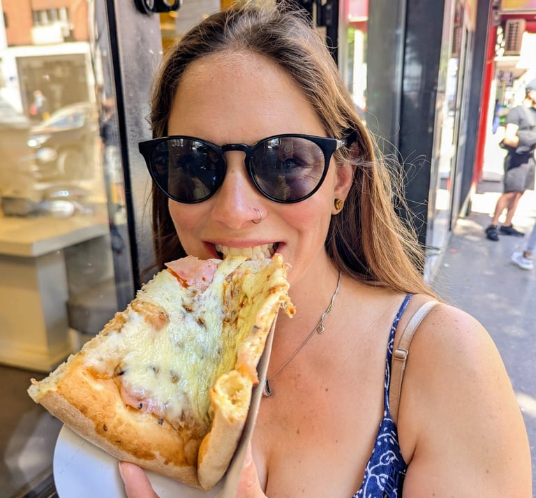 Bugs in sunglasses eats a cheesy slice of Roman-style pizza al taglio on a city street.