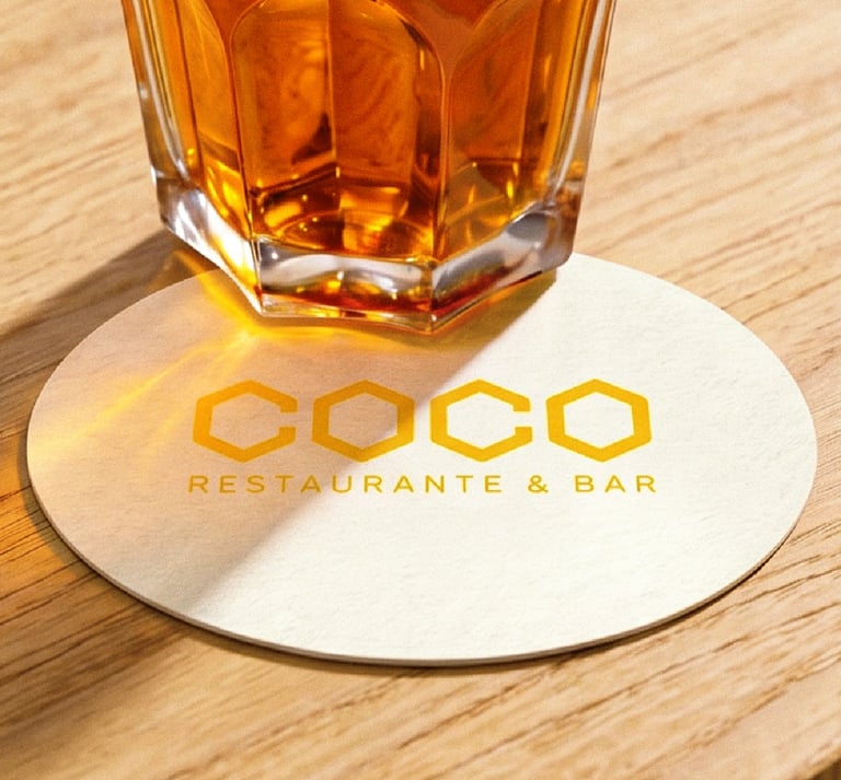 Posavasos con la marca sobre mesa de madera junto a un cóctel