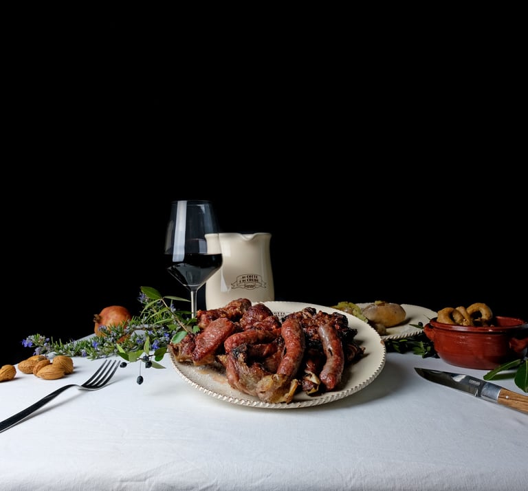 Traditional Italian dinner featuring grilled sausages, red wine, and savory sides on a white tablecloth.