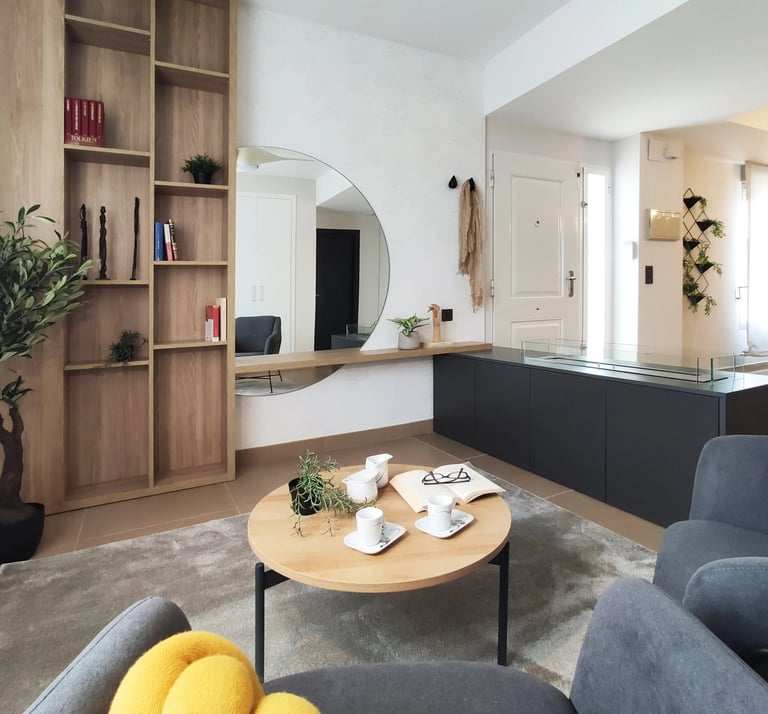 Decoración de interiores de zona relax con librería de madera, chimenea de bioetanol y butaca en San Antonio de Benaguér