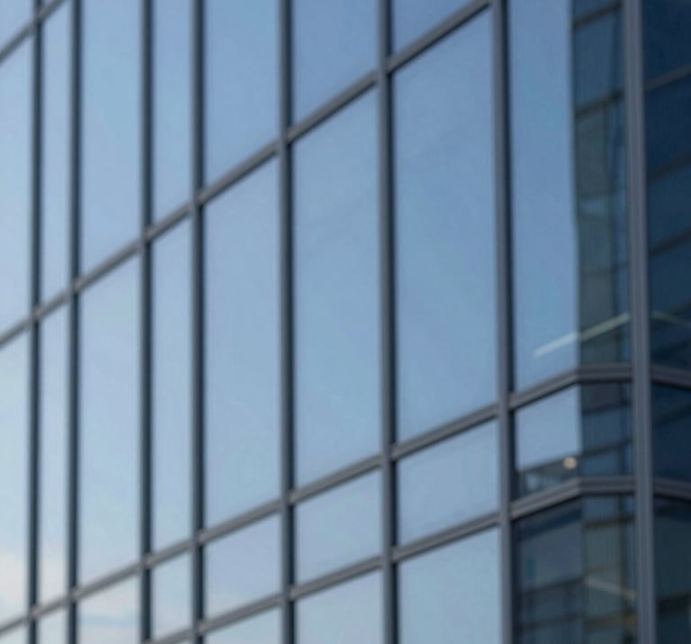 Abstract shot of architectural lines on a modern glass building, reflecting a clear blue sky, minimalist and sharp.