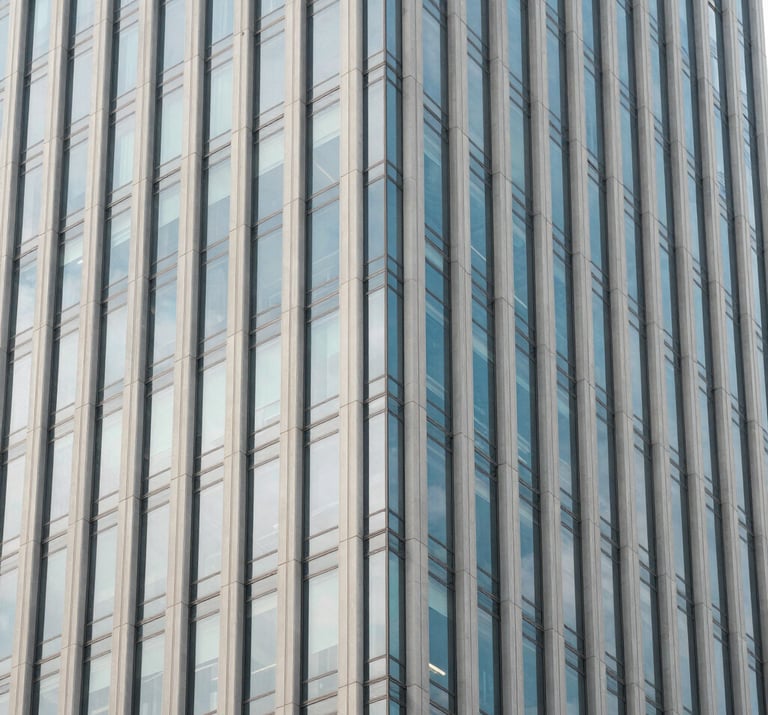 A minimalist architectural detail of a glass skyscraper in a North American city reflecting a pale blue sky. Clean lines, contemporary design, off-white and soft blue-grey tones.