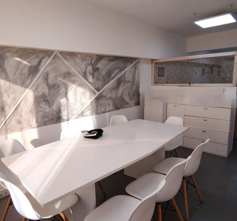 Sala de firmas en Red de Llaves, con mesa blanca, sillas modernas y luz natural por ventanales.