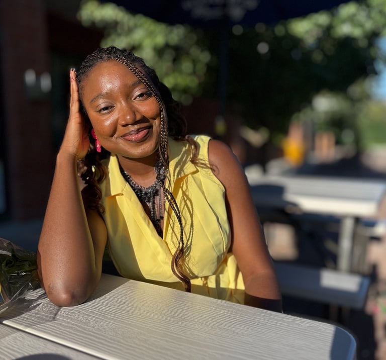 Iheoma Uzomba in yellow dress smiling.