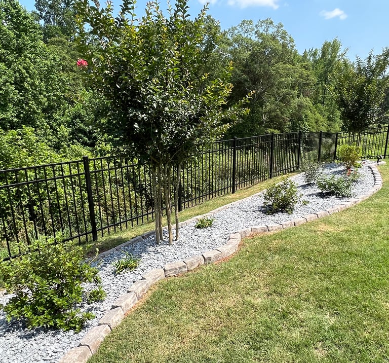 Created backyard flowerbed along the black fence with azaleas, butterfly bushes, roses, slate mulch and stone border.