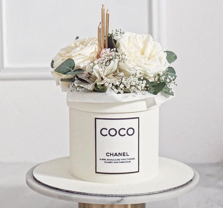 a chanel perfume bottle with flowers in a white container