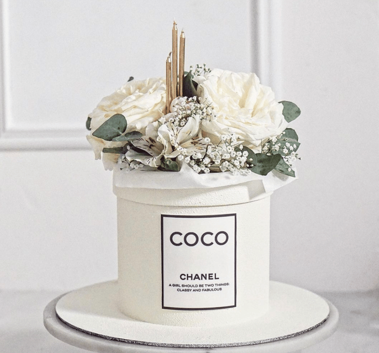 a chanel perfume bottle with flowers in a white container
