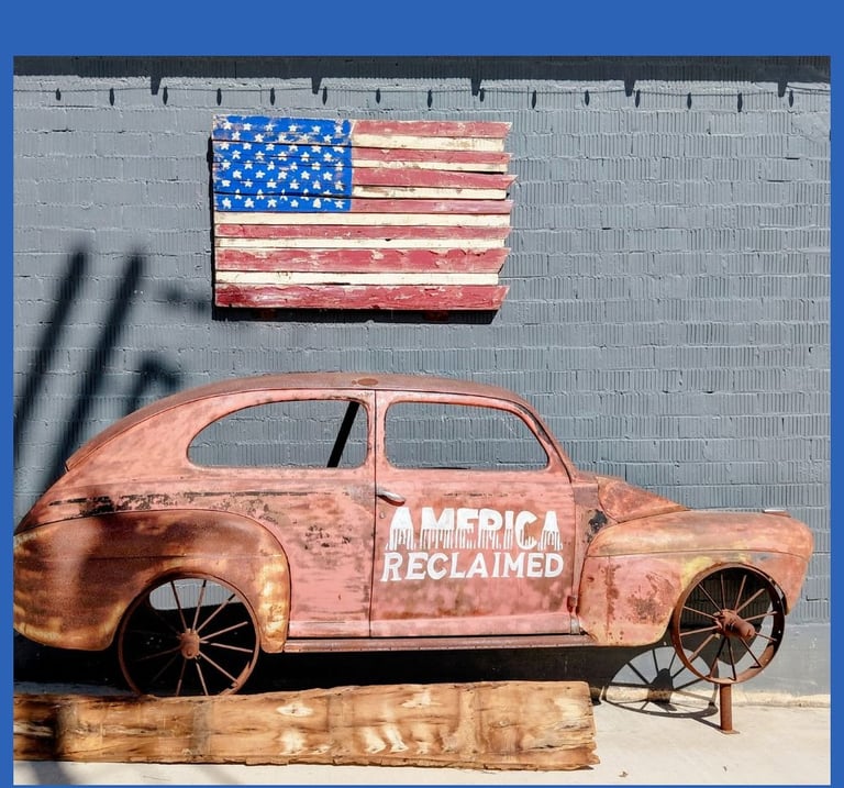 American flag displayed above a reclaimed metal art car sculpture.