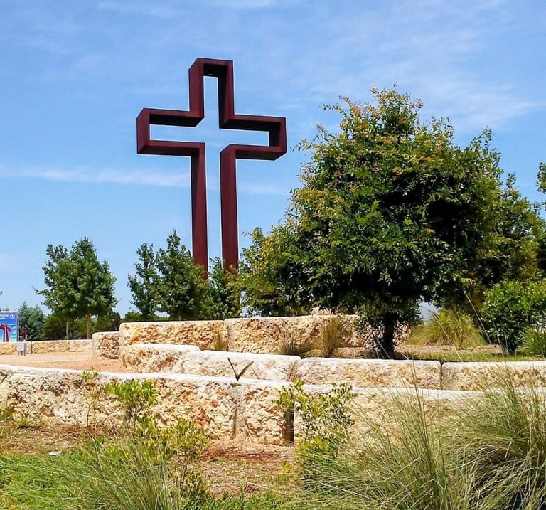 The empty cross standing above green trees