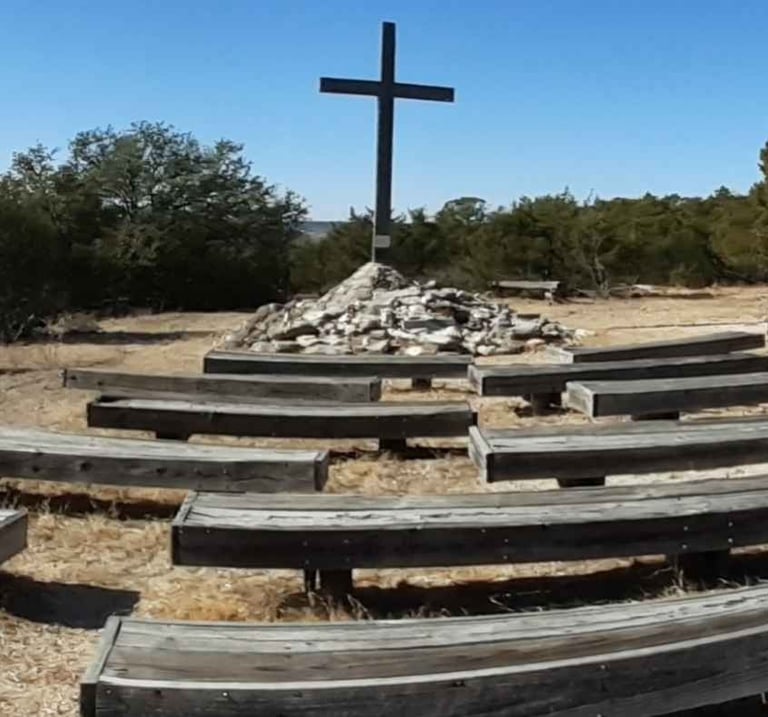 Wood cross behind rows of wood benches
