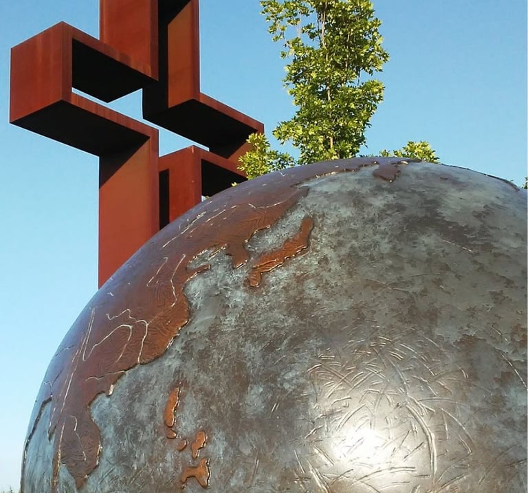 Empty cross behind large metal globe