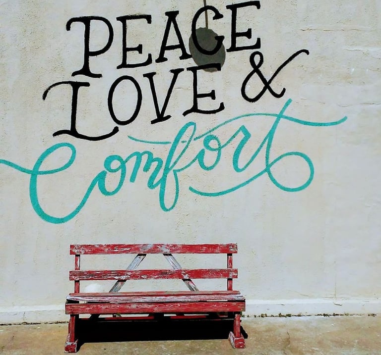 Peace Love and Comfort written on wall above red bench