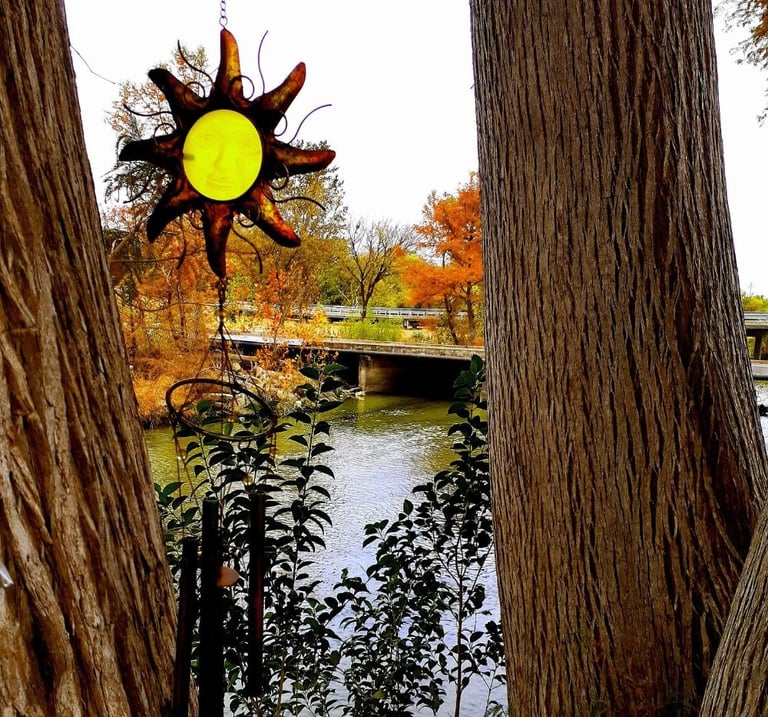 Yellow metal star hanging between two trees, with a river flowing under a bridge