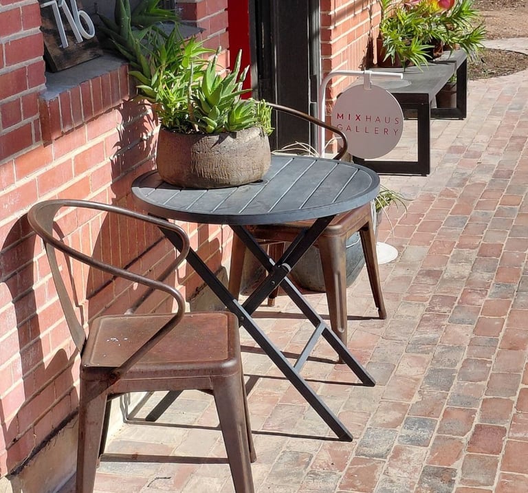 Two metal chairs and round table on brick sidewalk