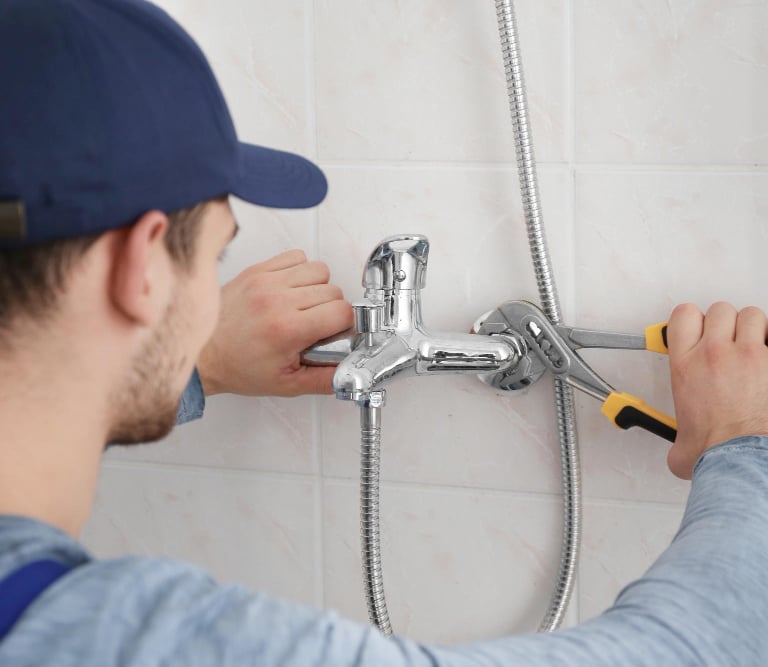 Plumber repairing a leaking shower tap, professional leaking shower repair service Auckland