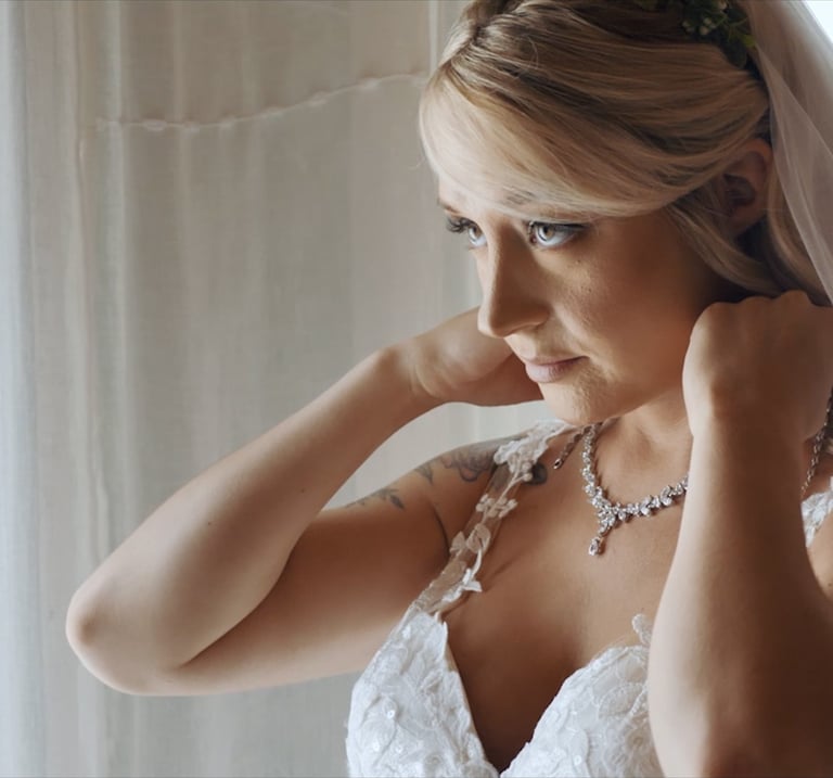 A bride putting on her necklace before her wedding ceremony