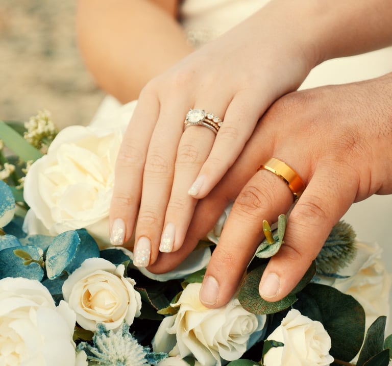 a bride and groom holding hands with their wedding rings
