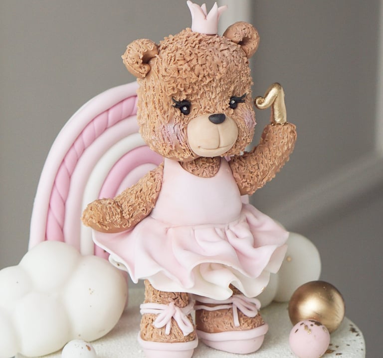 a teddy bear in a pink dress on a cake