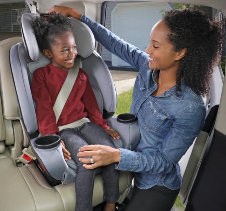 Mother putting child in car seat in car