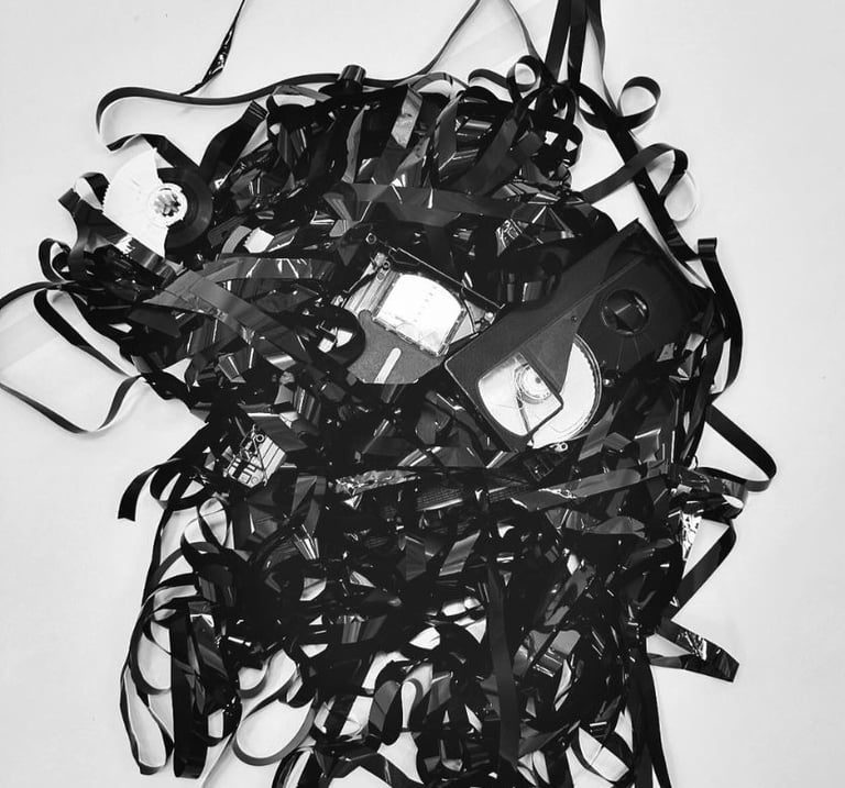 performance art installation hammer breaking old vhs tapes and unwinding the tape tapes in drag
