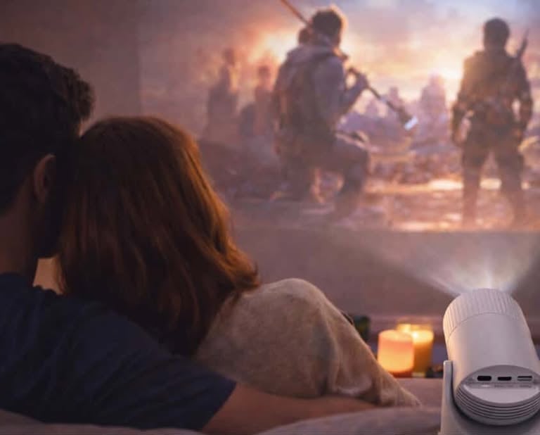 Couple watching a movie projected on the wall using a compact home projector