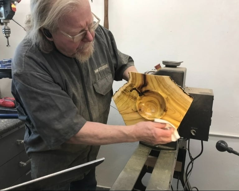 Woodturner Tom Baker at the lathe applying oil to Mulberry Crotch Natural Edge Winged Bowl