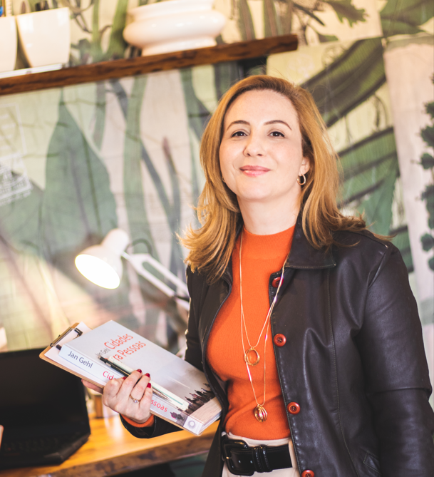 Professional woman in a leather jacket holding books in a stylish office workspace.