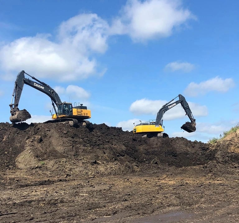 two excavators digging dirt on hill