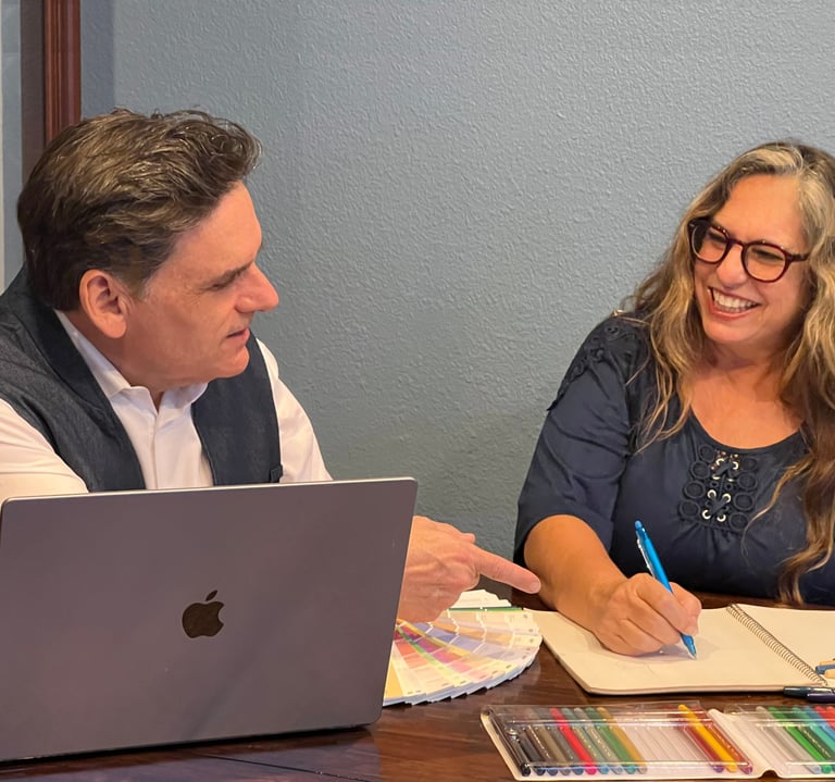 a man and woman sitting at a table with a laptop