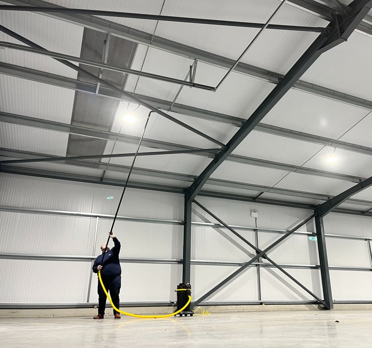 Technician vacuuming high level ceiling from the ground