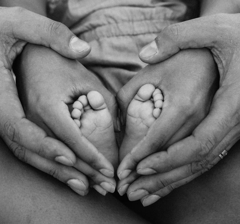 Parents holding babies feet in a heart shape
