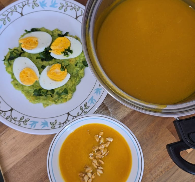 esta es una sopa de zappallo acompañando con un plato plano con aguacate en cama y huevoscocidos