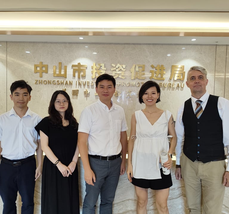 A group of professionals standing in front of the Zhongshan Investment Promotion Bureau sign.