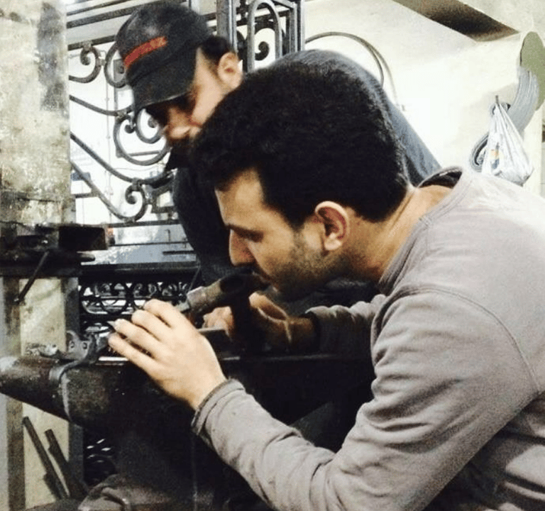 Un ferronnier artisan est en train de façonner une pièce métallique.