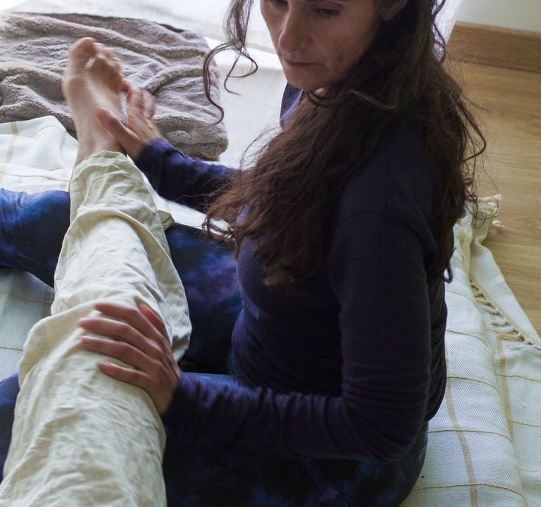 Juliette Maggu in Thai Yoga Massage Position mit Händen am Bein der massiertes Person 