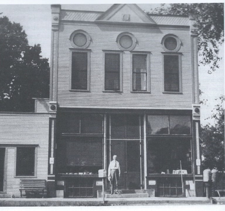 a two story white building with a man standing in front of it