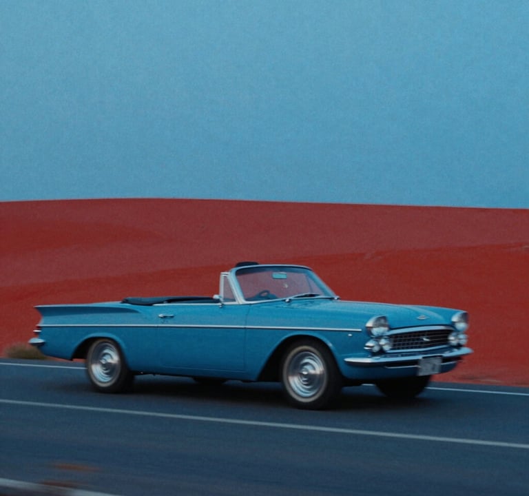 A cinematic wide shot of a 1960s convertible car driving through a landscape of flat #0050B3 blue and #D4202B red shapes. The composition is extremely asymmetric, following Godard's visual style. Heavy film grain and a sense of motion blur in a graphic, non-realistic way.