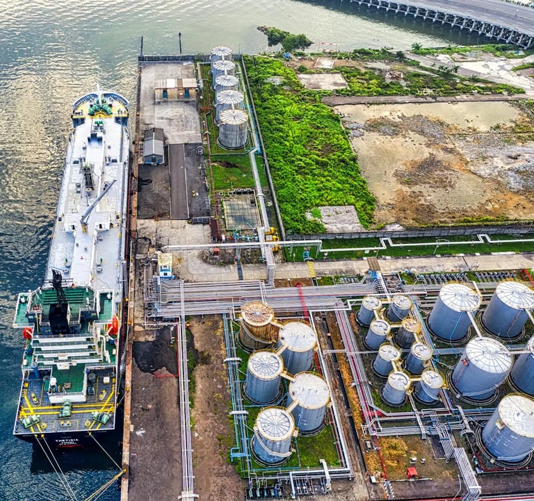 a large ship in the water with a large tanks in the background
