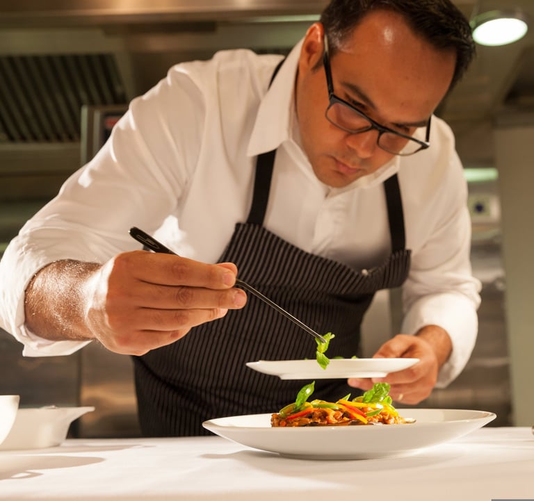 Um chef de cozinha finalizando um prato com delicadeza
