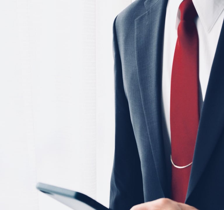 Um homem vestindo terno e gravata segurando um celular nas mãos