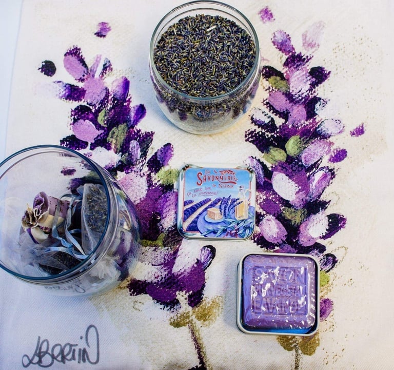 a table with a bowl of lavander seeds and a jar of dried herbs and a lavander soap in tin box