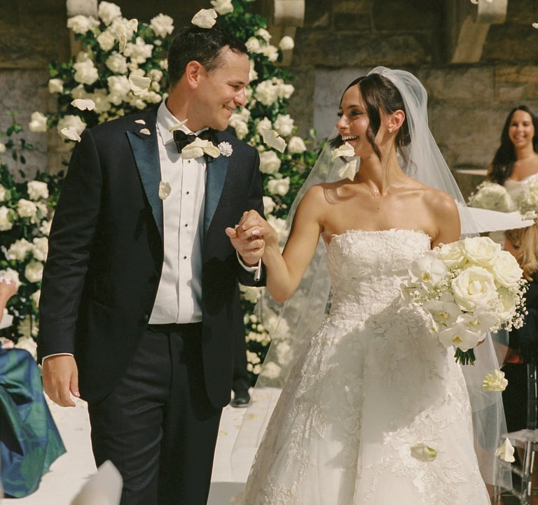 Happy just married couple walking down the aisle full of white flowers