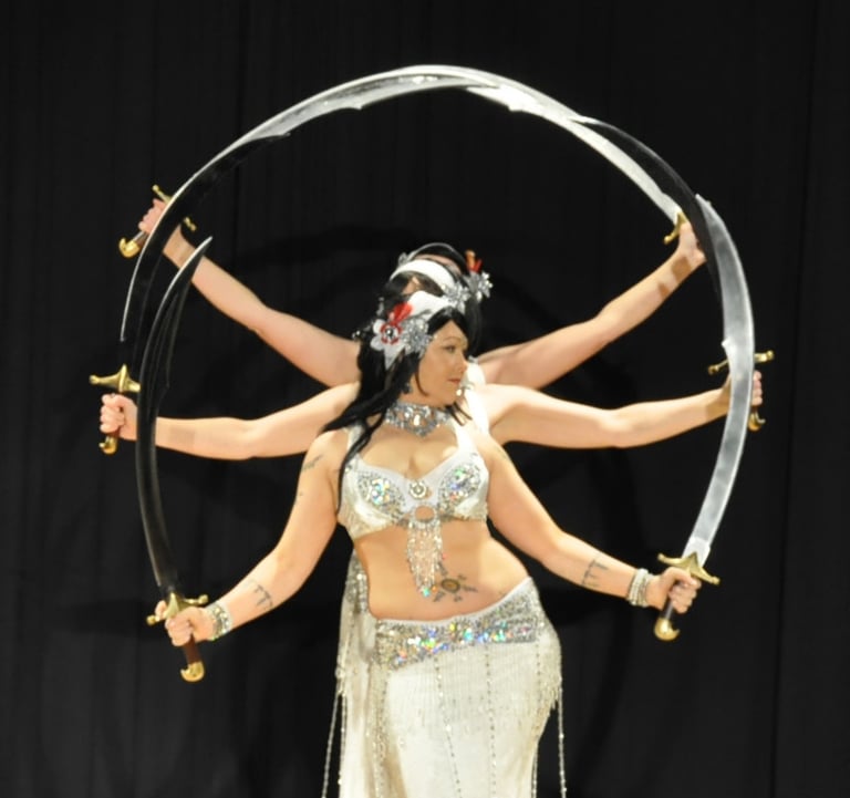 Shahravar and troupe Habibi Habibi of SLC dancing with double scimitars wearing white costumes