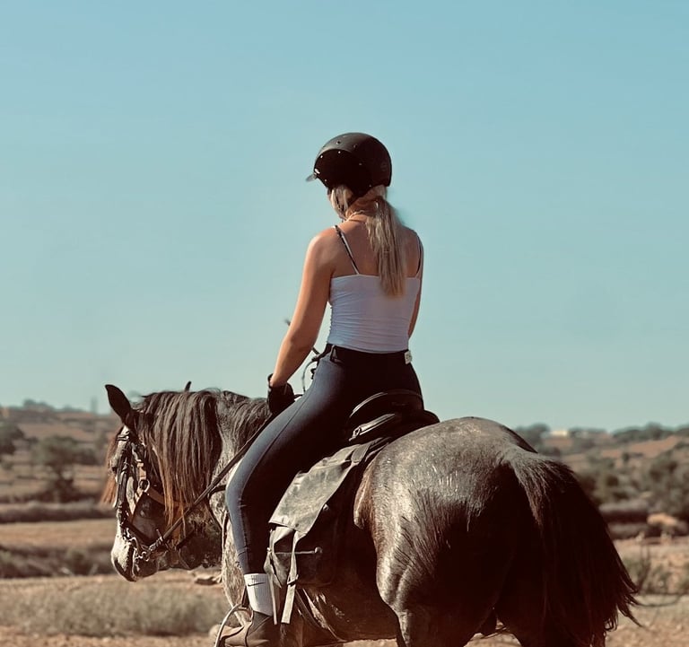 femme montant un cheval dans la campagne, avec un beau ciel bleu