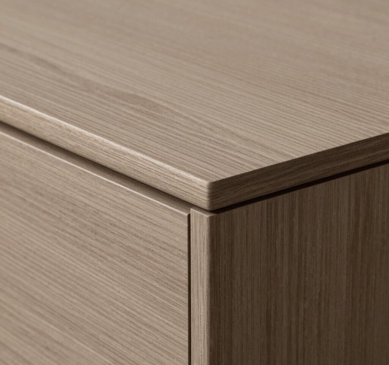 A detail shot of custom-made furniture featuring warm taupe wood and minimalist joinery, emphasizing the studio's focus on craftsmanship.