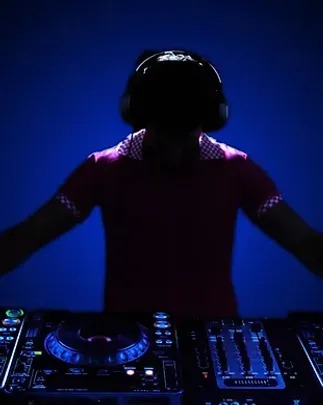 Silhouette of a disc jockey wearing a headset, DJing at turntables. DJ