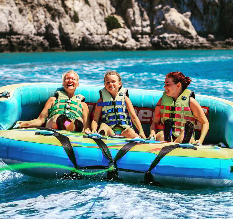 a group of people 2 women and 1 girl is riding a raft in Tsambika Beach Rhodes