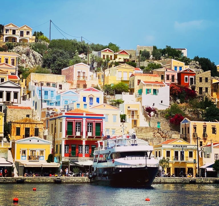 a boat in the water near a bunch of colorful buildings in Symi island in Greece