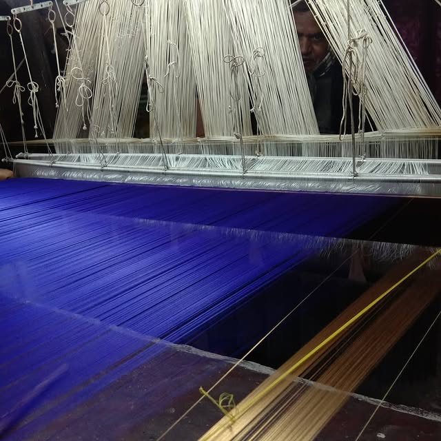a man is working on a blue and white weaving machine