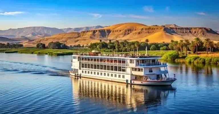 Vista panorâmica de um navio de cruzeiro de luxo navegando pelas águas calmas do Rio Nilo ao pôr do sol.